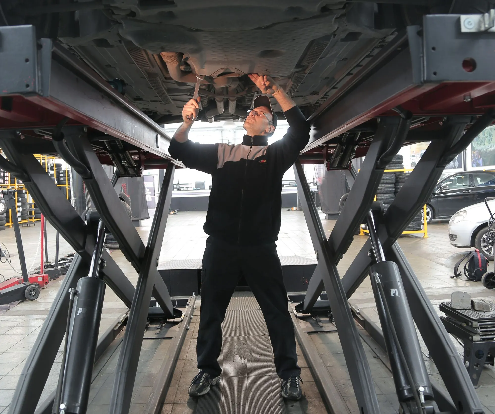 Fahrzeug auf der Hebebühne, ein Mechaniker arbeitet am Unterboden